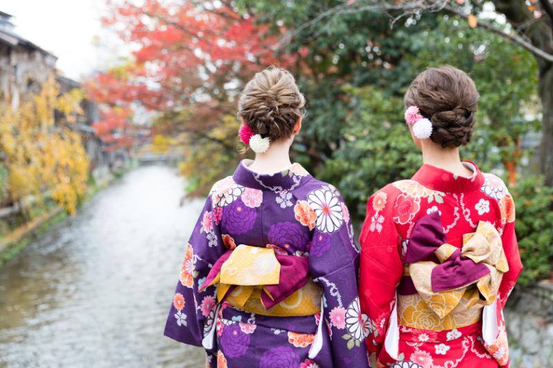 紅葉と川を眺める着物姿の女性2人組