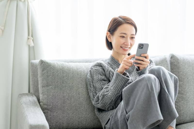 自宅でスマートフォンを操作する女性