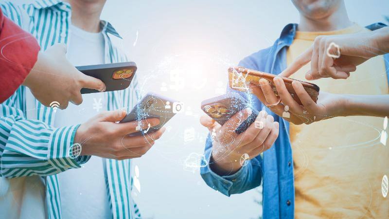 スマートフォンを近づけて操作する４人の人物