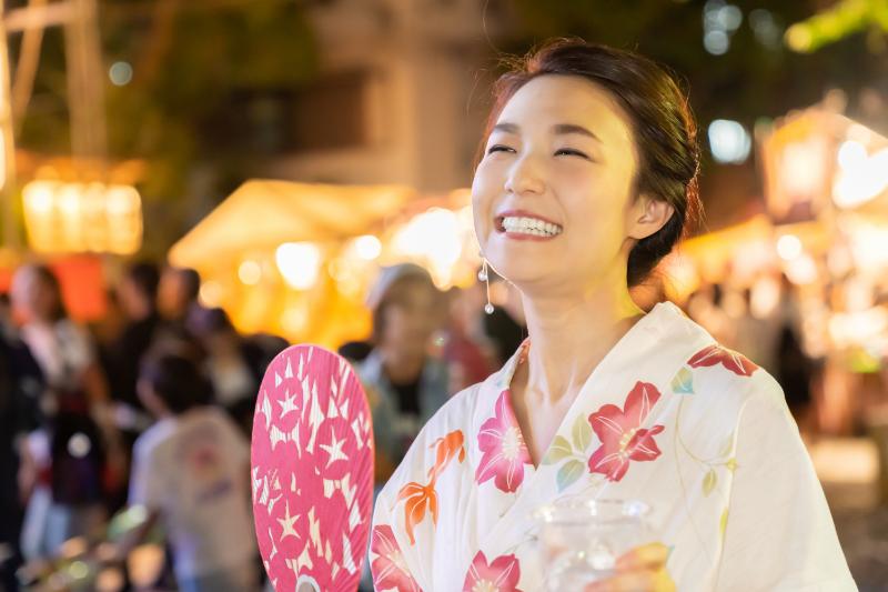 笑顔でうちわを持った浴衣の女性