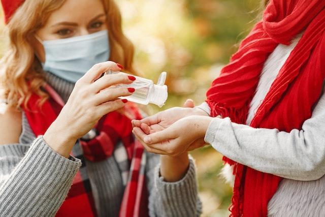 除菌液を相手の手に注ぐマスクをした女性