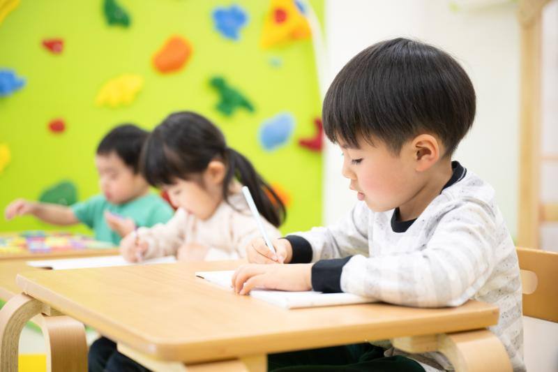 机上でノートにメモをする3人の子供