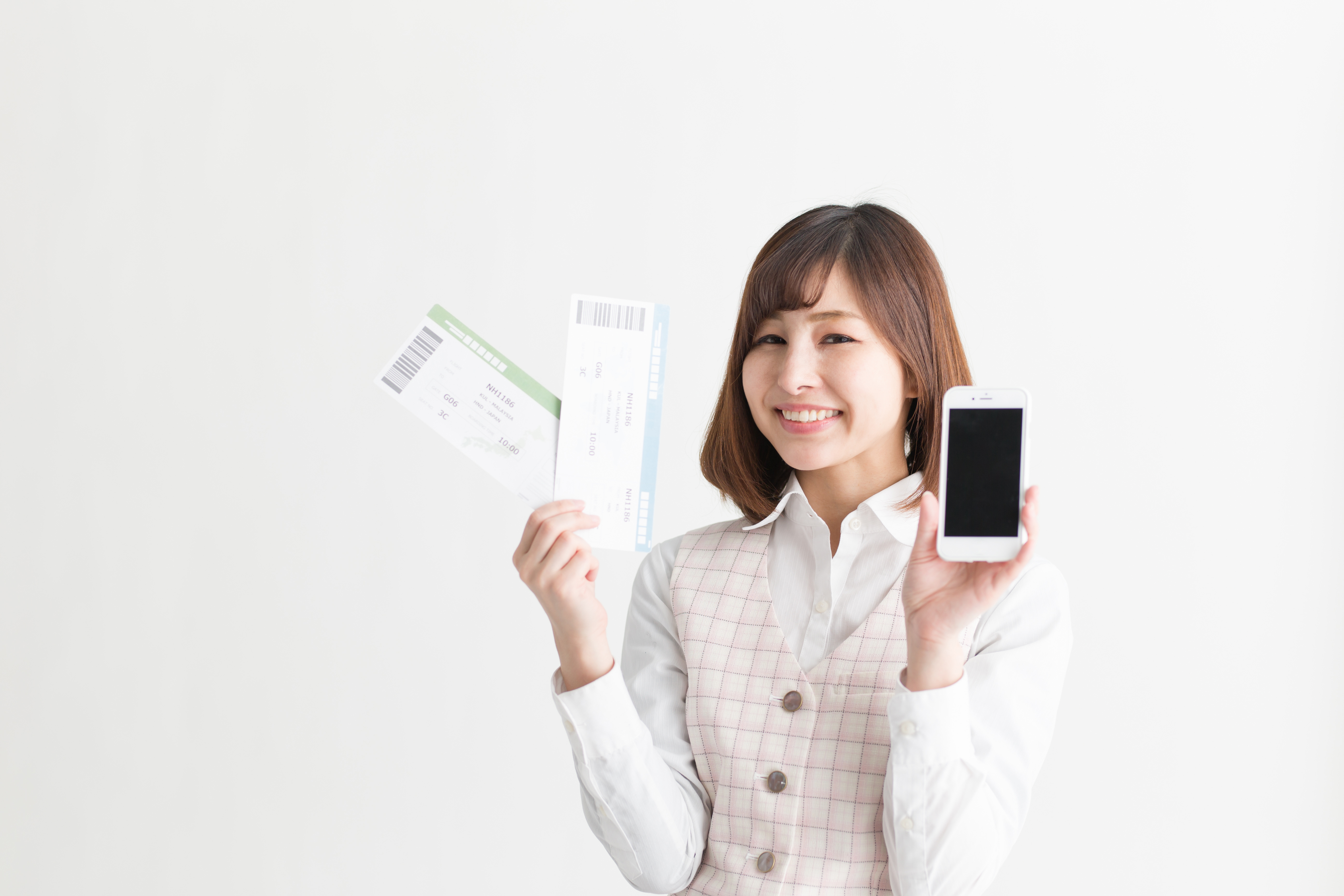 片手に紙チケット、片手にスマートフォンを掲げる女性