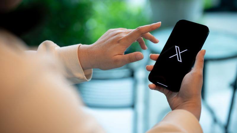 スマートフォンでXを操作する人物