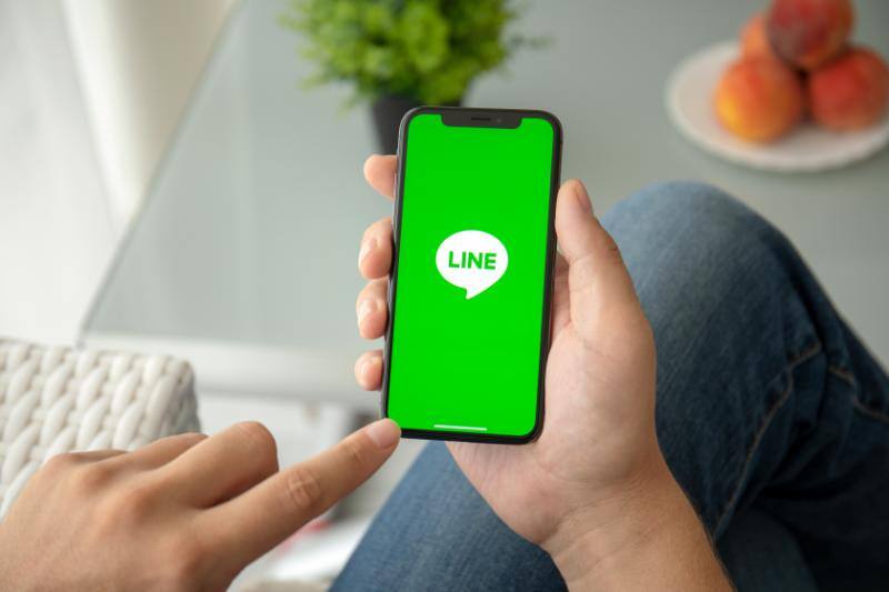 LINEアプリを起動したスマートフォンを指差す手