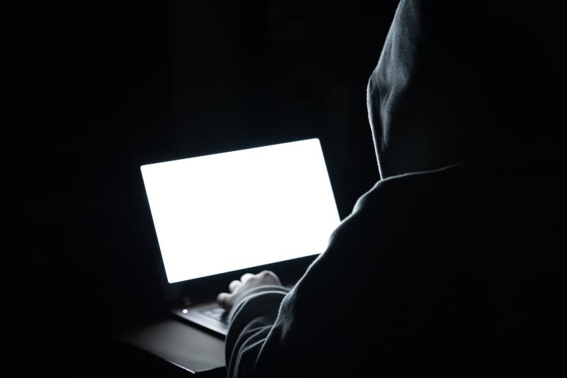 PCを操作するフードを被った怪しげな人物