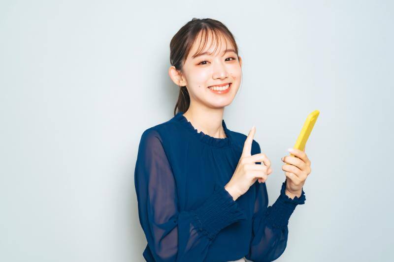 笑顔でスマートフォンを操作する女性