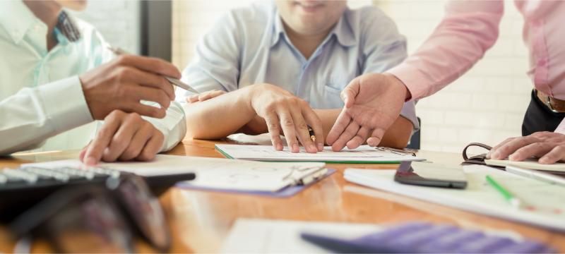 資料を指しながら議論する人々    